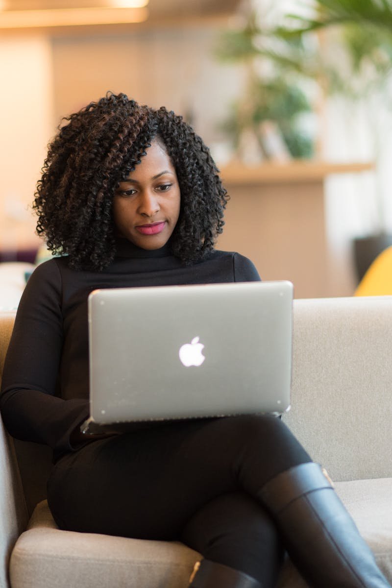 An African American woman working remotely on a laptop in a modern indoor setting.